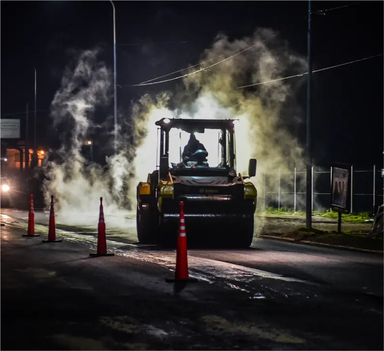 Máquina asfaltando una calle durante la noche